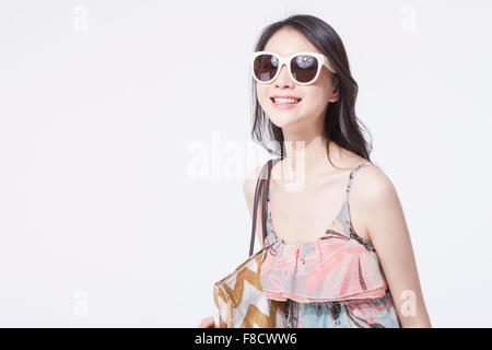 Donna con capelli lunghi in abito maxi sorridente con la sua borsa sulla sua spalla e lo sguardo in avanti Foto Stock