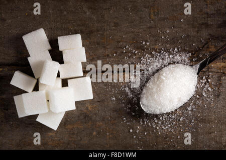 Zucchero bianco in cucchiaio d'argento su tavola di legno Foto Stock