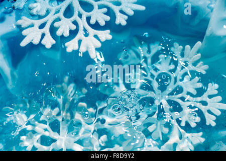 Il simbolo del fiocco di neve si scioglie in acqua di ghiaccio gocce raffreddare macro sfondo blu Foto Stock