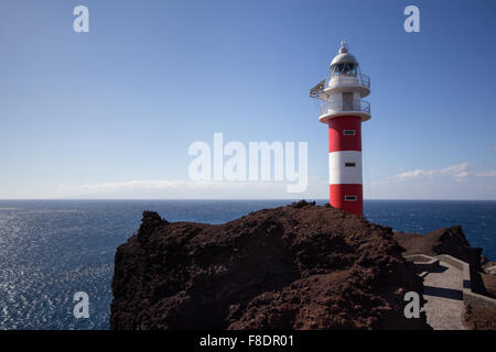 Rosso, bianco faro con sfondo oceano su roccia Foto Stock