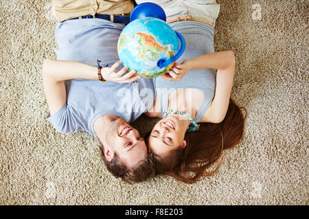 Un soggiorno riposante giovane con globo facendo piani per le vacanze Foto Stock