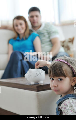 Giovani parrent a casa con bel bambino realizzare risparmi e messo monete soldi nel salvadanaio Foto Stock