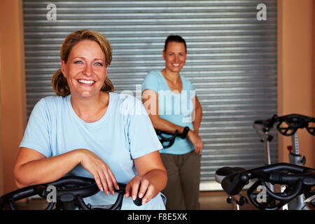 Due donne sorridente in piedi nella camera di filatura in una palestra Foto Stock