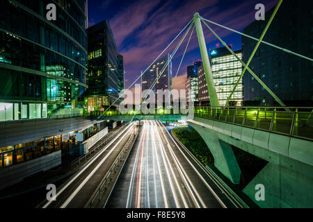 Ponte pedonale e moderni edifici adiacenti ad una strada di notte a La Défense di Parigi, Francia. Foto Stock