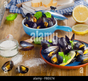 Piastre di cozze cotte al vapore su un sfondo di legno. Foto Stock