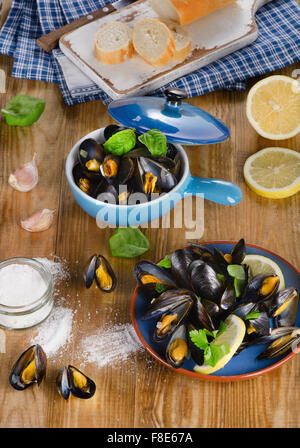 Piastre di cozze cotte al vapore su sfondo di legno. Vista da sopra Foto Stock