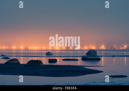Passeggiata sulle luci di notte nebbiosa, rocky seacoast davanti Foto Stock