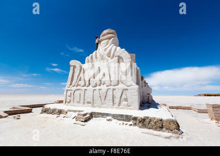 Giovane uomo in piedi sulla parte superiore della Parigi Dakar enorme scultura di sale di Uyuni. Questo monumento è dedicato Foto Stock