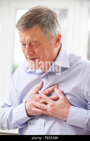 Senior uomo che soffre di attacco di cuore in casa Foto Stock