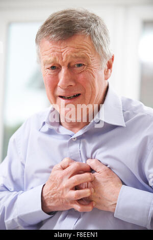 Senior uomo che soffre di attacco di cuore in casa Foto Stock