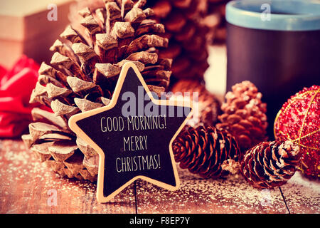 Il testo buongiorno buon natale scritto in una stella sulla lavagna un rustico di una superficie di legno con alcune pigne nelle quali, un rosso Foto Stock