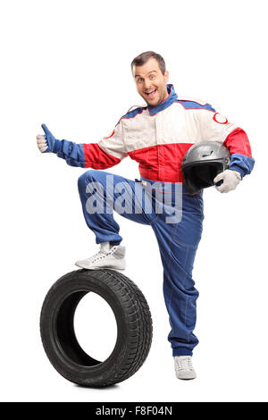 A piena lunghezza Ritratto di un entusiasta car racer tenendo un casco e dando un pollice in alto isolato su sfondo bianco Foto Stock