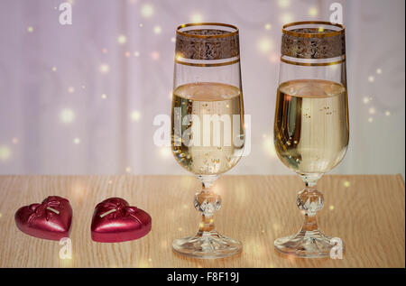 Su un tavolo vicino alla finestra ci sono due belle di vetro riempita con champagne. Prossimi due candele a forma di cuore. Foto Stock