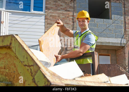 Builder di mettere i rifiuti nel cassonetto Foto Stock