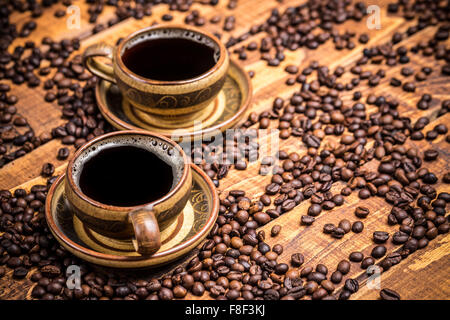 Tazze di caffè sul tavolo in legno con fagioli diffusa Foto Stock