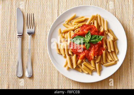 La pasta di grano con la salsa di pomodoro sulla piastra bianca sul tavolo di legno Foto Stock