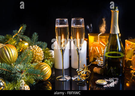 Festosa vita ancora - due bicchieri di champagne con bottiglia, candele, doni, orologio da tasca e le decorazioni di Natale su sfondo nero. Foto Stock