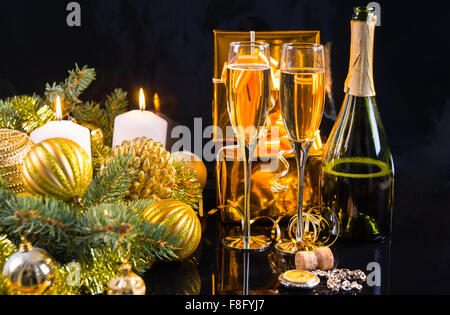 Luxury Gold a tema sfondo di Natale con una bottiglia e bicchieri di champagne, di dono, di decorazioni e candele accese su uno sfondo scuro. Foto Stock