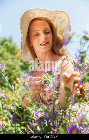 La donna caucasica ammirando fiori Foto Stock