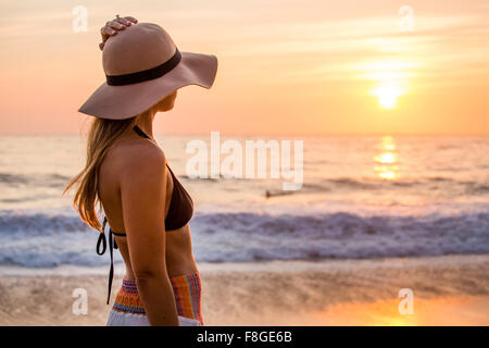La donna caucasica ammirando il tramonto e oceano Foto Stock