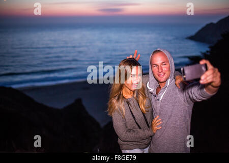 Coppia caucasica tenendo selfie presso la spiaggia Foto Stock