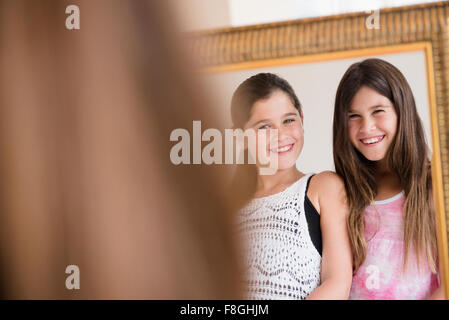 Caucasian gemelle ammirando stessi nel mirror Foto Stock