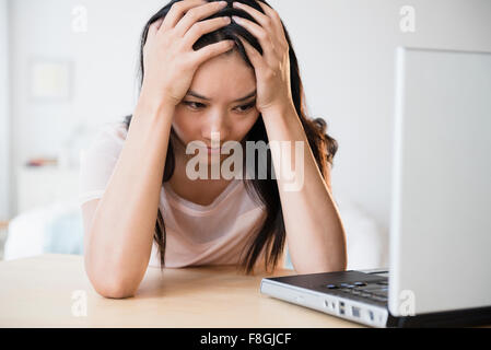 Frustrati donna cinese utilizzando laptop Foto Stock