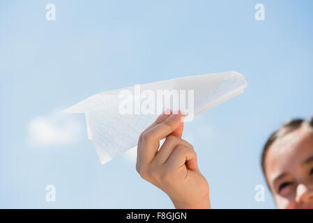 Ragazza con aeroplano di carta sotto il cielo blu Foto Stock