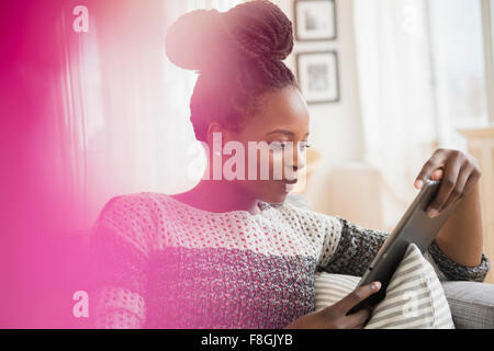 Donna nera con tavoletta digitale sul divano Foto Stock