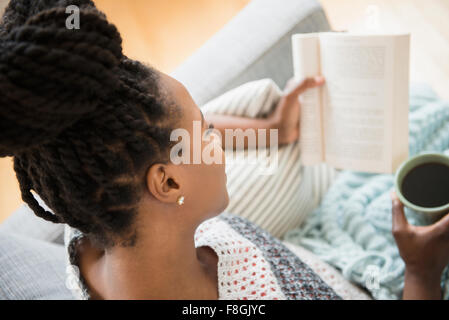 Donna nera libro di lettura e di bere il caffè Foto Stock
