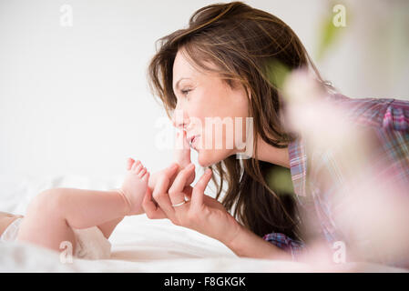 Madre baciare i piedi di bambina Foto Stock