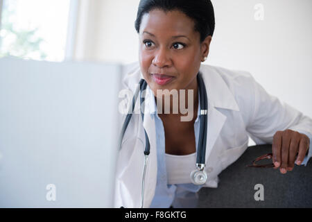 Medico nero utilizzando computer portatile in ufficio Foto Stock