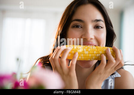 Donna ispanica mangiare sulla pannocchia di mais Foto Stock