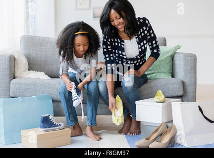 Madre e figlia cercando su scarpe sul divano Foto Stock