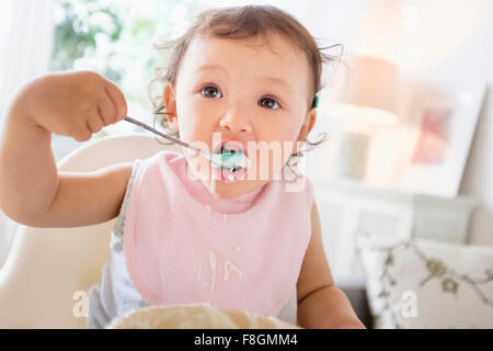 Razza mista Baby girl mangiare yogurt Foto Stock