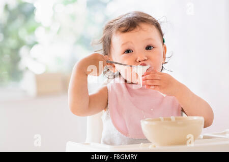 Razza mista Baby girl mangiare yogurt Foto Stock