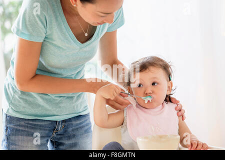 Alimentazione madre bimba in sedia alta Foto Stock