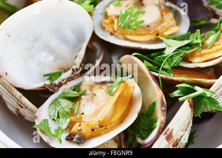 Close-up di Le vongole cotte al vapore nel recipiente bianco sul tavolo di legno Foto Stock