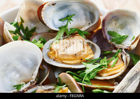 Close-up di Le vongole cotte al vapore nel recipiente bianco sul tavolo di legno Foto Stock