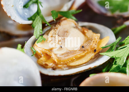 Close-up di Le vongole cotte al vapore nel recipiente bianco sul tavolo di legno Foto Stock
