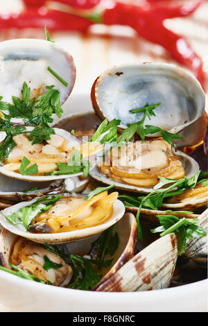 Close-up di Le vongole cotte al vapore nel recipiente bianco sul tavolo di legno Foto Stock