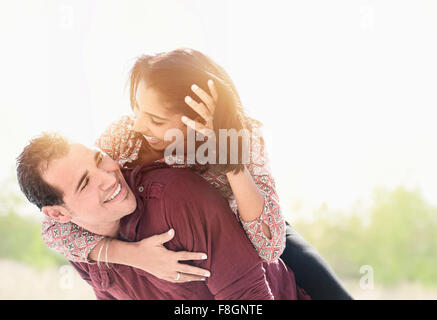 Uomo ispanico che trasportano ragazza piggyback Foto Stock