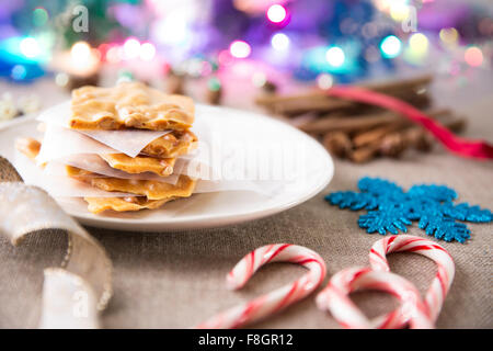 Scena festiva con fragile di arachidi su di una piastra e candy canne e altre decorazioni di Natale Foto Stock