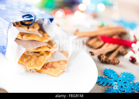 Peanut fragile la fuoriuscita del sacco regalo di Natale che circonda gli elementi di piastra. Foto Stock