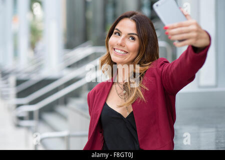 Imprenditrice ispanica tenendo selfie all'aperto Foto Stock