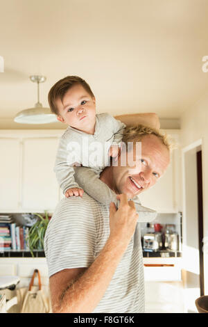 Padre bambino portando figlio sulle spalle Foto Stock