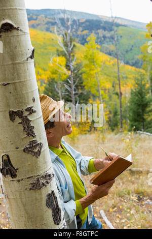 Uomo libro lettura nella foresta di autunno Foto Stock