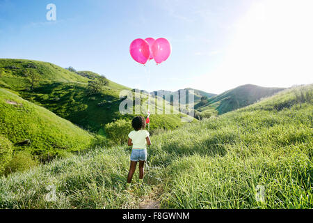 Ragazza nera con palloncini sulla collina rurale Foto Stock