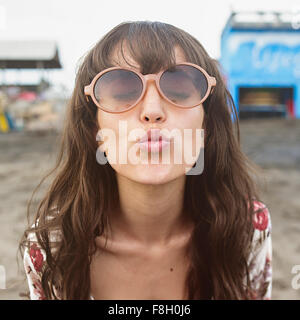La donna caucasica in occhiali da sole il raggrinzimento di kiss in spiaggia Foto Stock