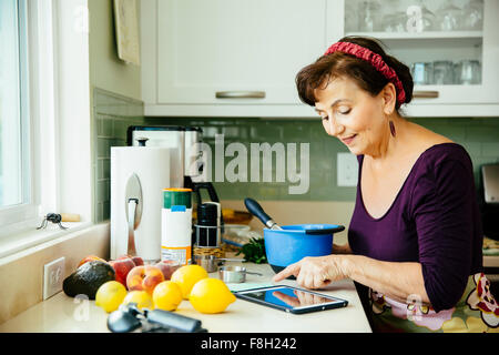 La donna caucasica utilizzando digitale compressa in cucina Foto Stock